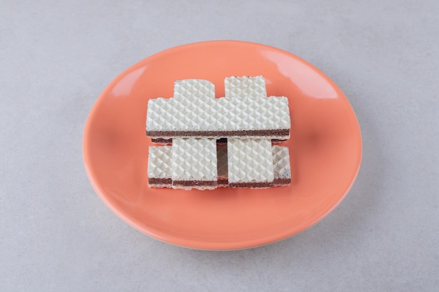 Free photo crispy wafers on a plate on marble table.