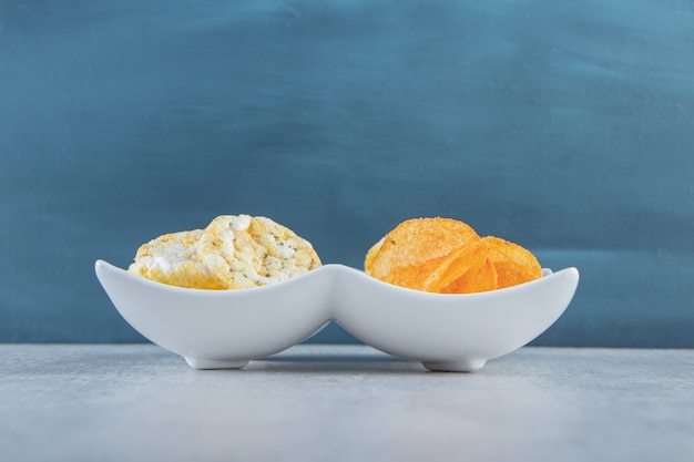 Free photo crispy wholegrain rice cakes and spicy chips in white bowls.