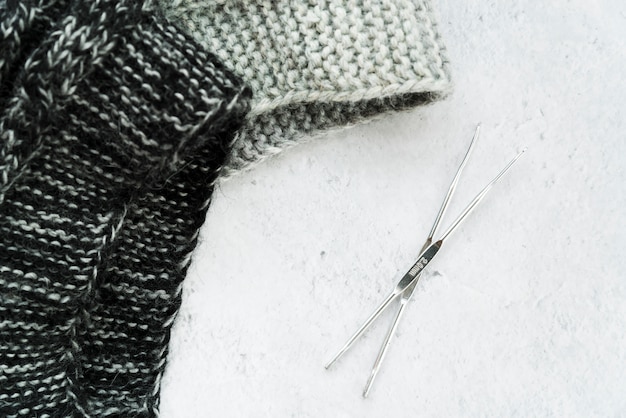 Free photo crochet needles and knitwear fabric on white textured backdrop