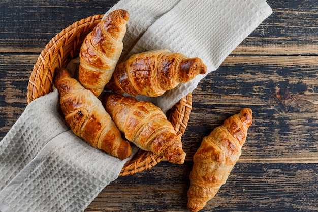 Free photo croissant in a basket with cloth on a wooden table. flat lay.