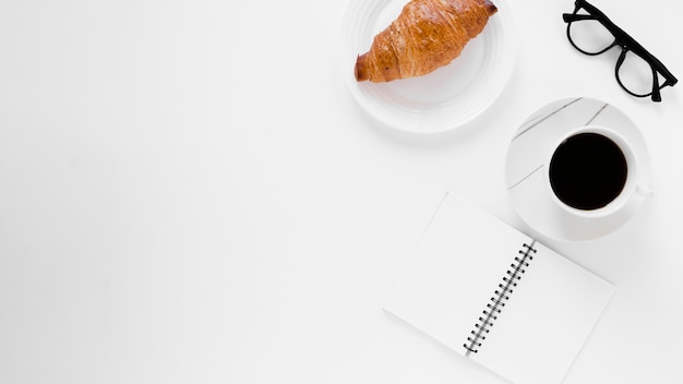 Croissant black coffee and notebook with copy space