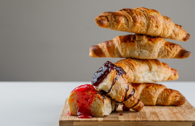 Croissant on a cutting board with jam side view