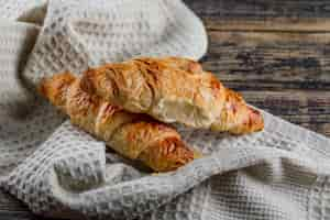 Foto gratuita vista dell'angolo alto del croissant sull'asciugamano di cucina e di legno