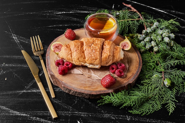 Free photo croissant with berries on wooden platter.