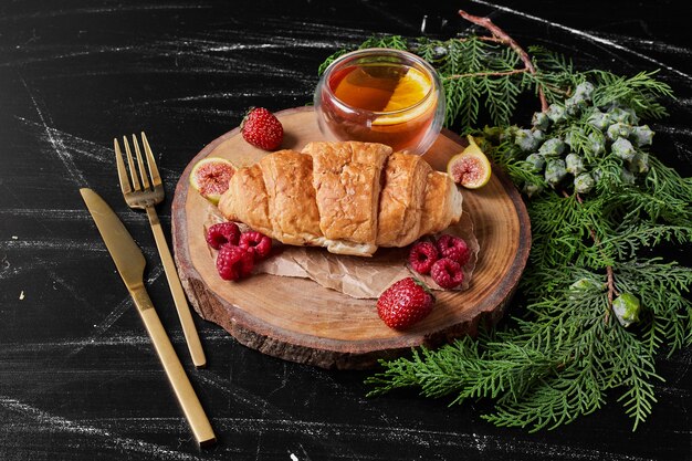 Croissant with berries on wooden platter.