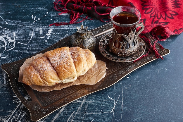 A croissant with a glass of tea. 