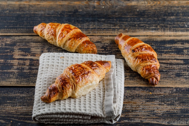 Croissant on wooden and kitchen towel, high angle view.