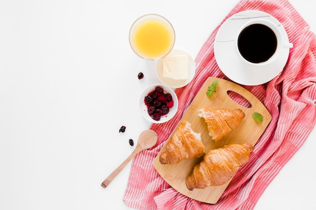 Croissants on cutting board with coffee and orange juice