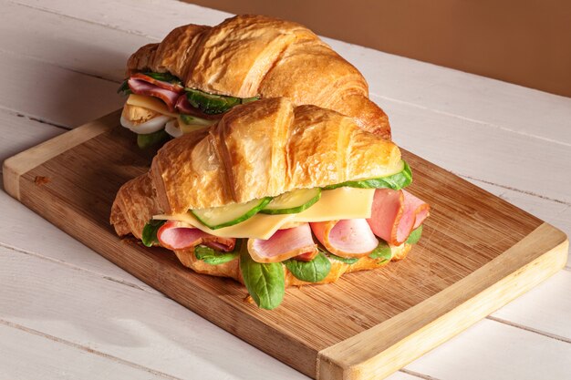 Croissants sandwiches on the wooden cutting board