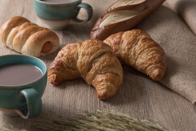 Croissant con pane e tazza di caffè su fondo in legno