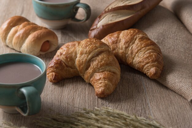 Croissants with bread and coffee cup on wooden background