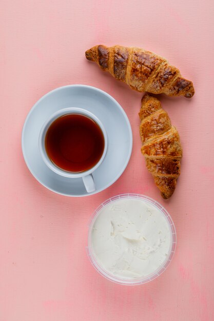 クリームチーズとクロワッサン、ピンクのテーブルでお茶のトップビュー