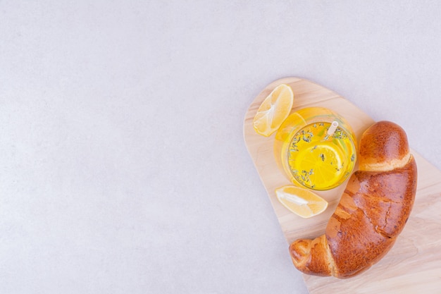 Foto gratuita croissant con un bicchiere di limonata sulla superficie bianca