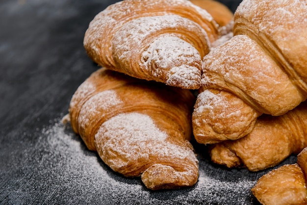  croissants with powdered sugar on grey table.