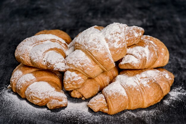  croissants with powdered sugar on grey table.