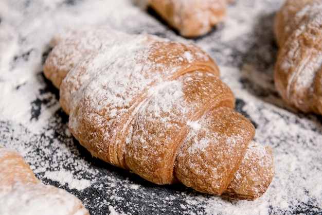  croissants with powdered sugar on grey table.