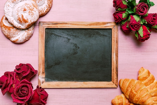 Croissants with red roses bouquet and chalkboard 