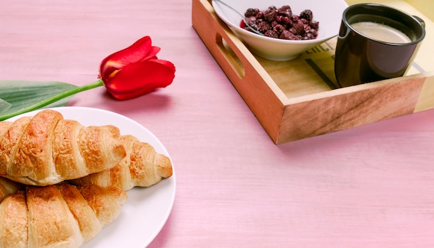 Croissants with red tulip and tray with berries 