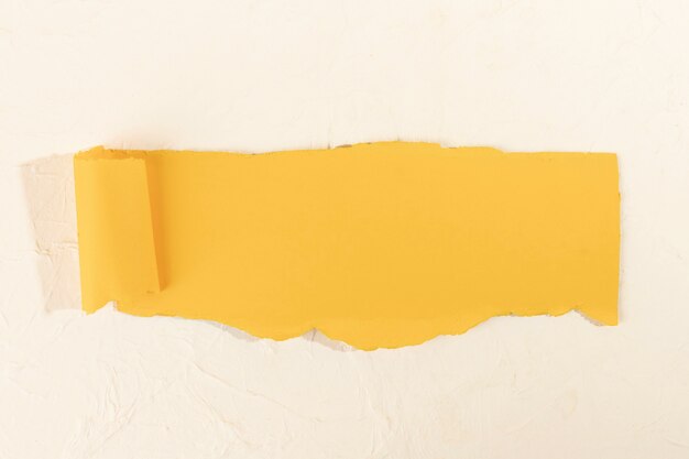 Кривая желтая полоска бумаги на бледно-розовом фоне