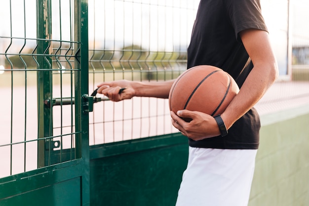 Crop anonymous athlete male opening basketball court 