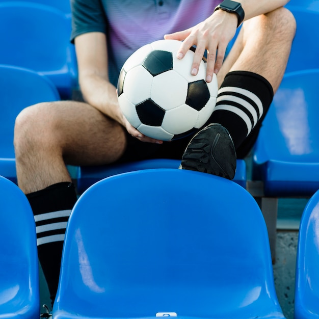 Crop athlete with soccer ball on stadium