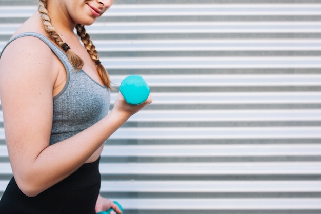 Crop athletic woman with dumbbell