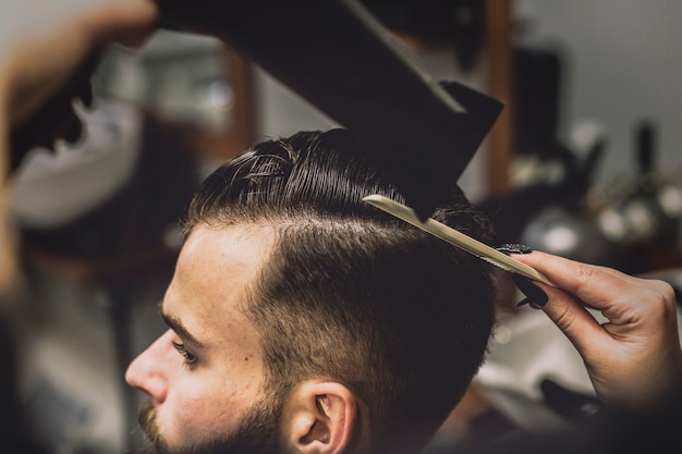 Foto gratuita ritaglia il barbiere che asciuga i capelli del cliente
