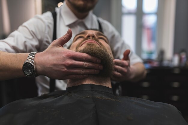 Crop barber styling beard of customer