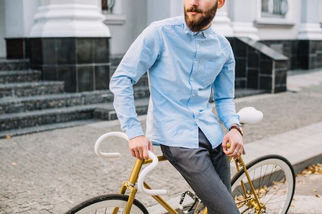Crop bearded man leaning on bicycle