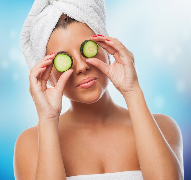 crop of beautiful brunette in towel with cucumber