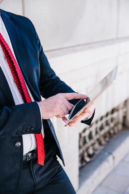 Free photo crop businessman browsing tablet on street