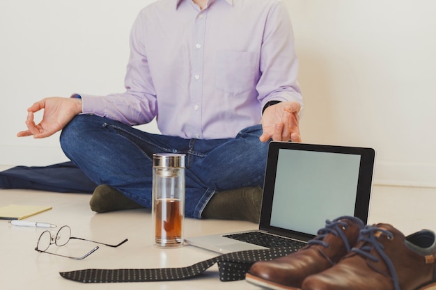 Crop businessman meditating on floor