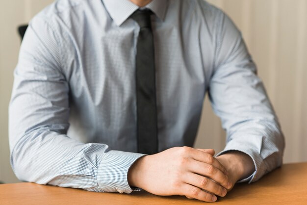 Crop businessman sitting at table