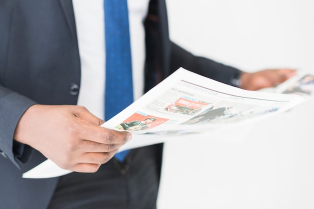 Crop businessman standing with newspaper