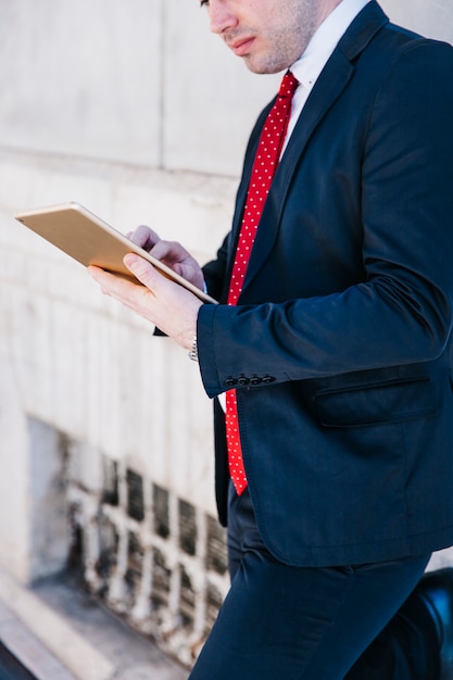 Free photo crop businessman using tablet on street