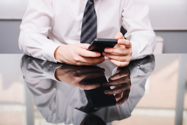 Crop businessman with smartphone