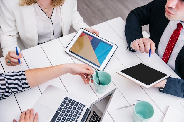 crop businesspeople with gadgets at desk