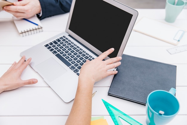 Ritaglia la donna di affari che mostra il computer portatile ai colleghi