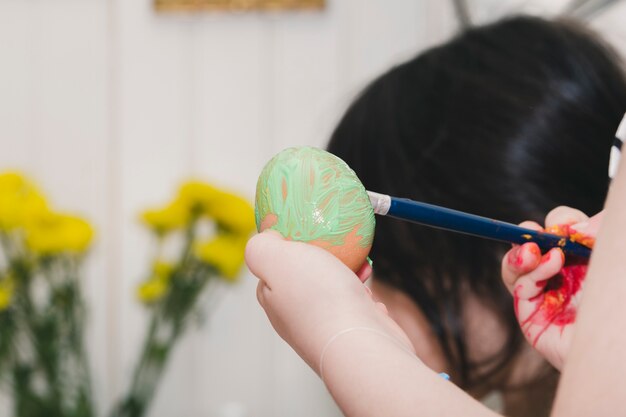 Free photo crop child painting egg with green