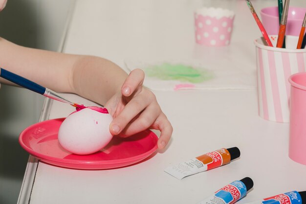 Crop child painting egg
