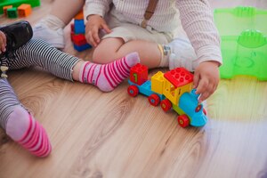 Coltivi i bambini sul pavimento con i giocattoli