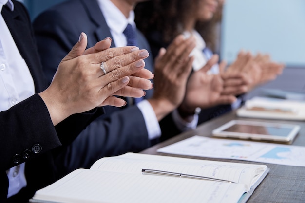 Crop colleagues clapping on meeting