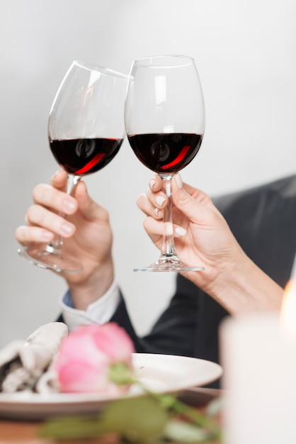 Crop couple clinking with wineglasses