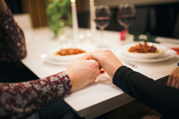 Crop couple holding hands on table