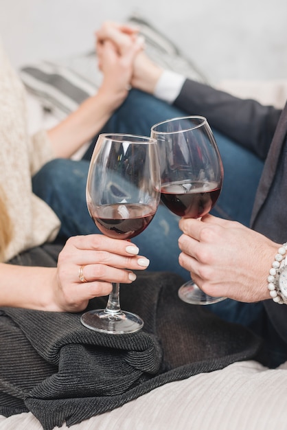 Crop couple in love clinking with wineglasses