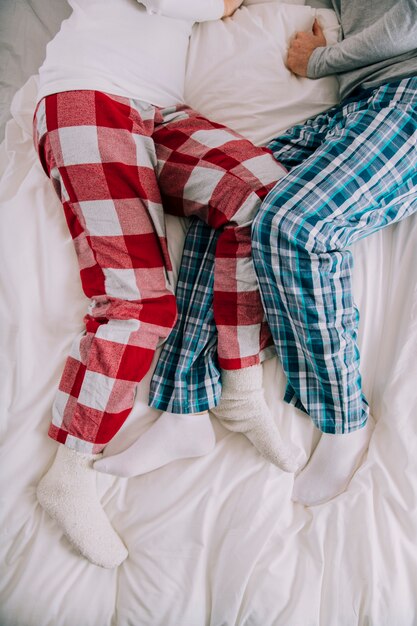 Crop couple lying on bed