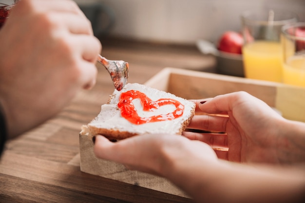 Crop couple making toast with jam