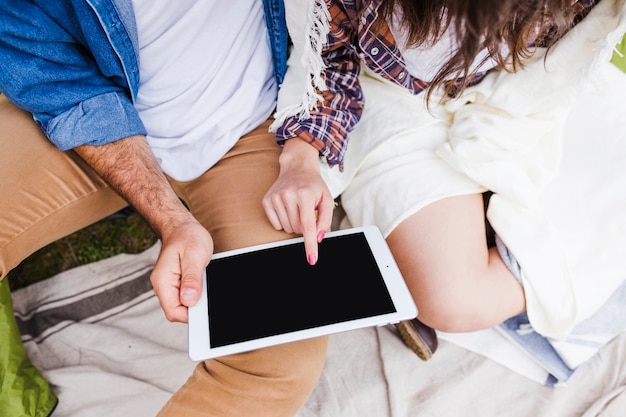 Crop couple using tablet in nature