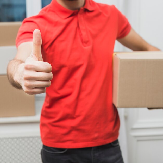 Crop courier gesturing thumb-up