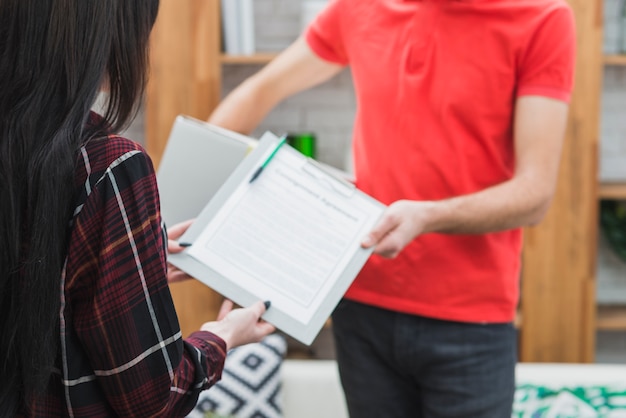 Crop courier giving clipboard to customer